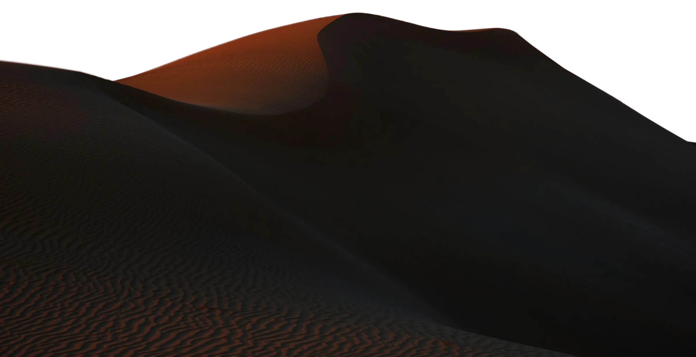 Wind-shaped sand dunes at dusk under a warm sky